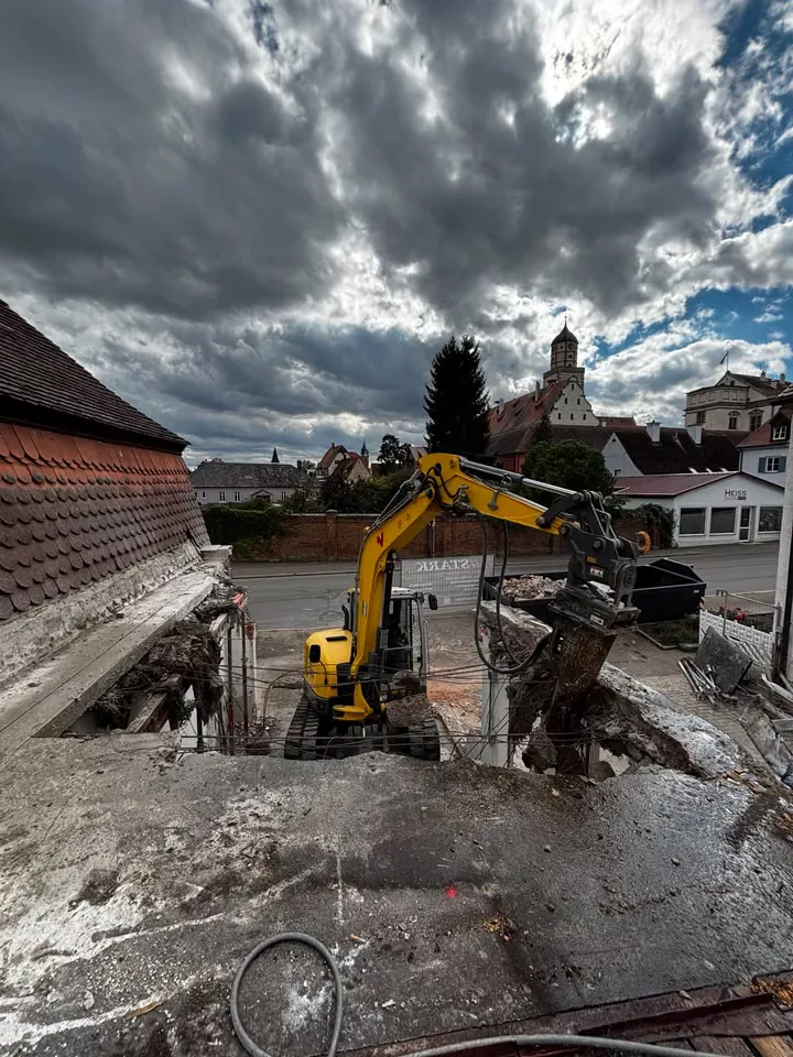 Hydraulikhammer am Minibagger bricht eine Betondecke im Ortskern auf