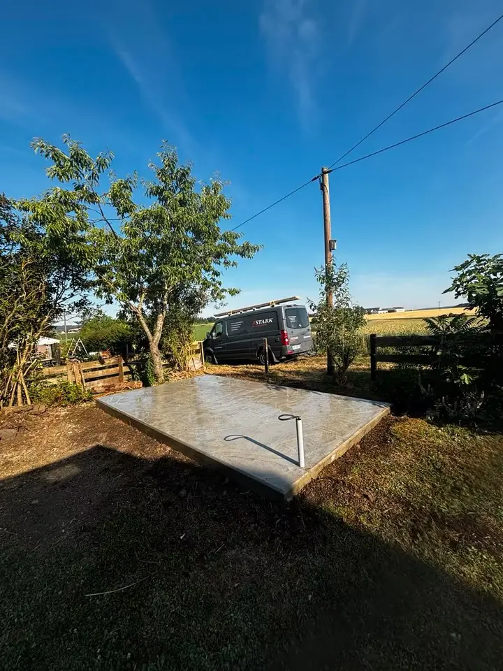 Fertige Bodenplatte aus Beton im Garten, dahinter der Firmenwagen mit STARK-Schriftzug