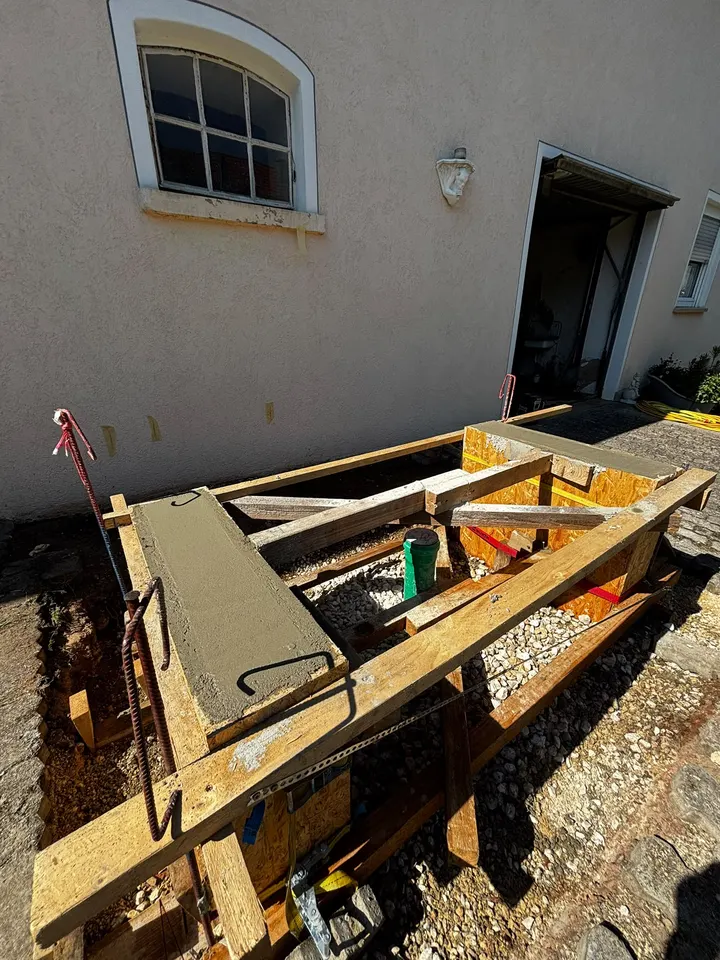 Holzschalung für ein Wärmepumpenfundament im Ortbeton-Verfahren an einer Hauswand